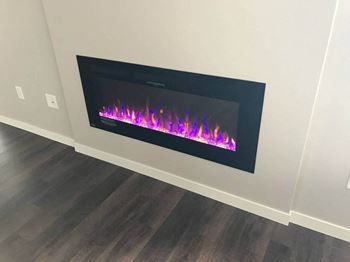 an electric fireplace in a room with a wooden floor at Grayhawk Apartments, North Dakota